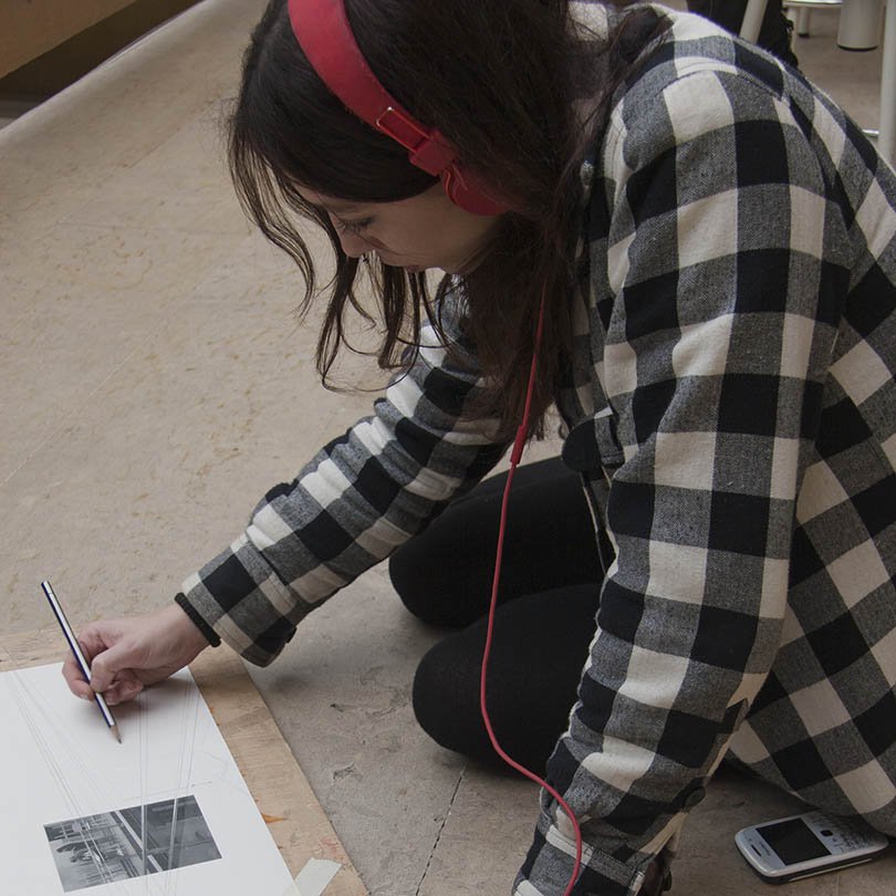 Alumna dibujando sentada en el suelo